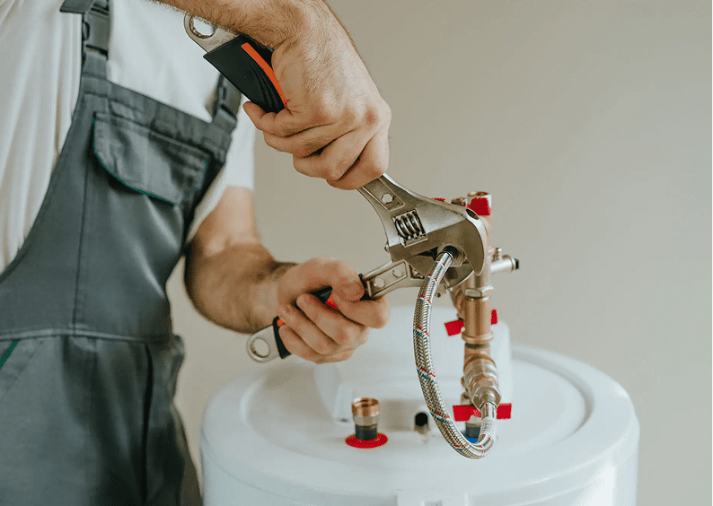 Plumber fixing water heater with wrench