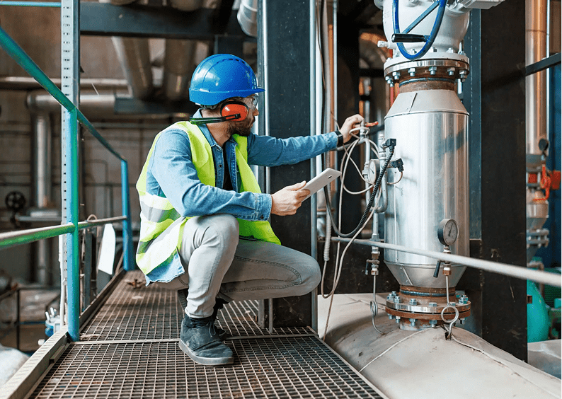 Worker in safety gear examining machinery